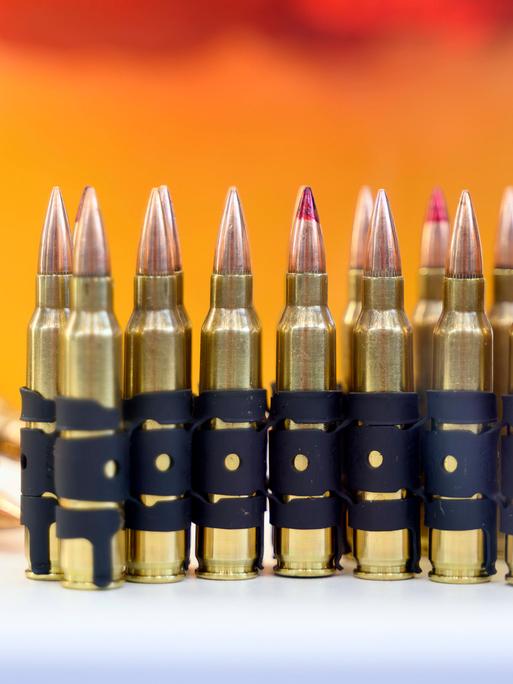 Munition ist auf einer Messe ausgestellt. Dabei sind mehrere Patronen nebeneinander gestellt und werden so präsentiert. 
