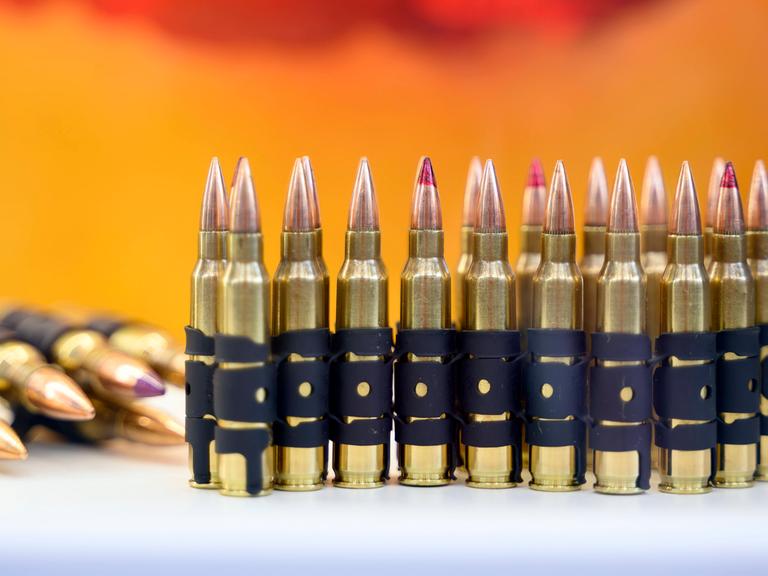 Munition ist auf einer Messe ausgestellt. Dabei sind mehrere Patronen nebeneinander gestellt und werden so präsentiert. 