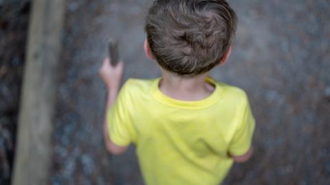 Man sieht einen Jungen von hinten und oben einen Weg entlang laufen.