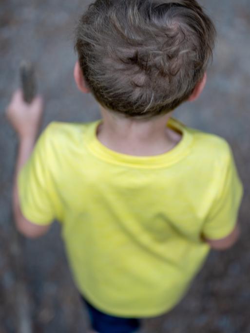 Man sieht einen Jungen von hinten und oben einen Weg entlang laufen.