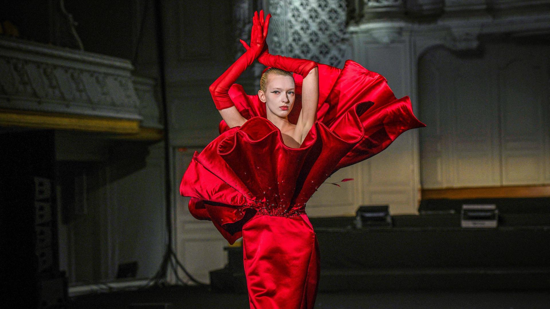 Ein Model posiert in einem extravaganten knallroten Kleid bei einer Modenschau im Rahmen der Paris Fashion Week.