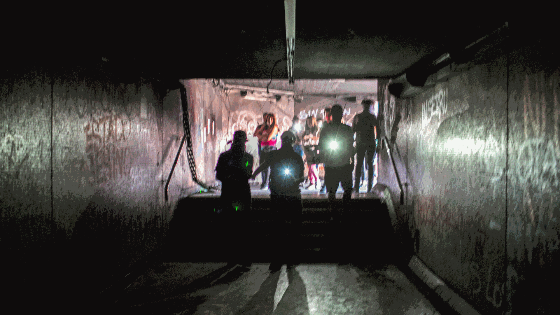 In einem Tunnel sind im Hintergrund Menschen mit Taschenlampen.