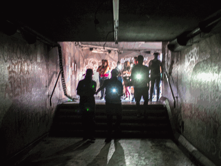In einem Tunnel sind im Hintergrund Menschen mit Taschenlampen.