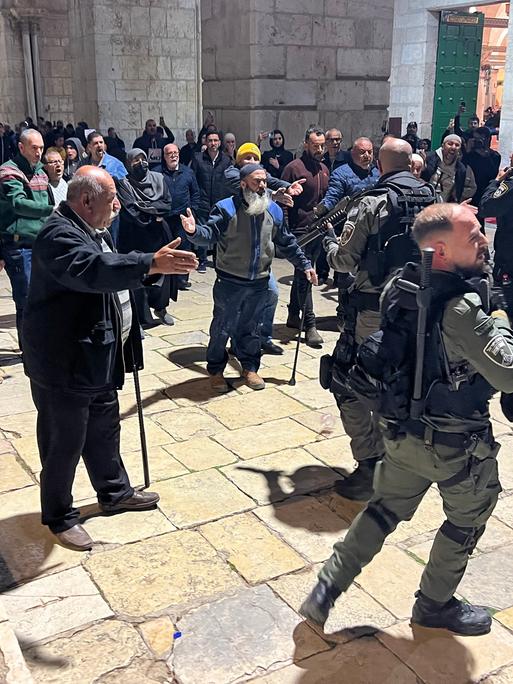 Bewaffnete israelische Soldaten auf dem Gelände der Al-Aksa-Moschee stehen vor einer Menschenmenge.