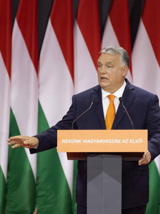 Der ungarische Ministerpräsident Viktor Orbán hält eine Rede. Im Hintergrund hängen Flaggen mit den ungarischen Landesfarben.