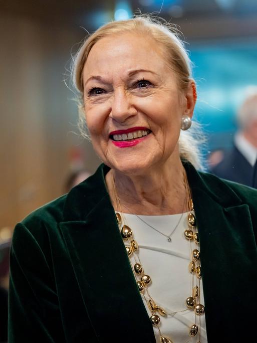 Benita Ferrero-Waldner lächelt in festlicher Kleidung ihr Gegenüber im Off an.