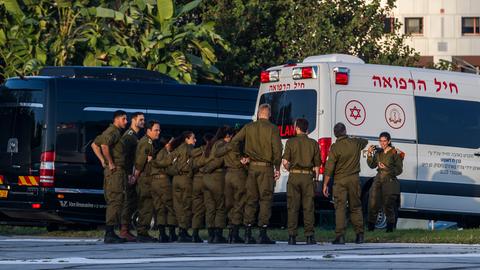 Israelisches Militärpersonal wartet vor einem Krankenhaus auf die freigelassenen Geiseln. Im Hintergrund ist ein Krankenwagen zu sehen.