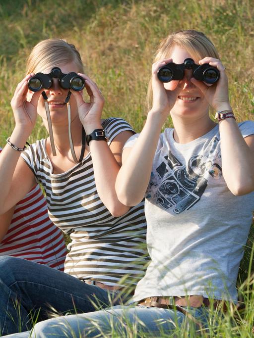 Drei junge Frauen mit Feldstechern in Beuel am Vilicher Bach blicken Richtung Kamera. 