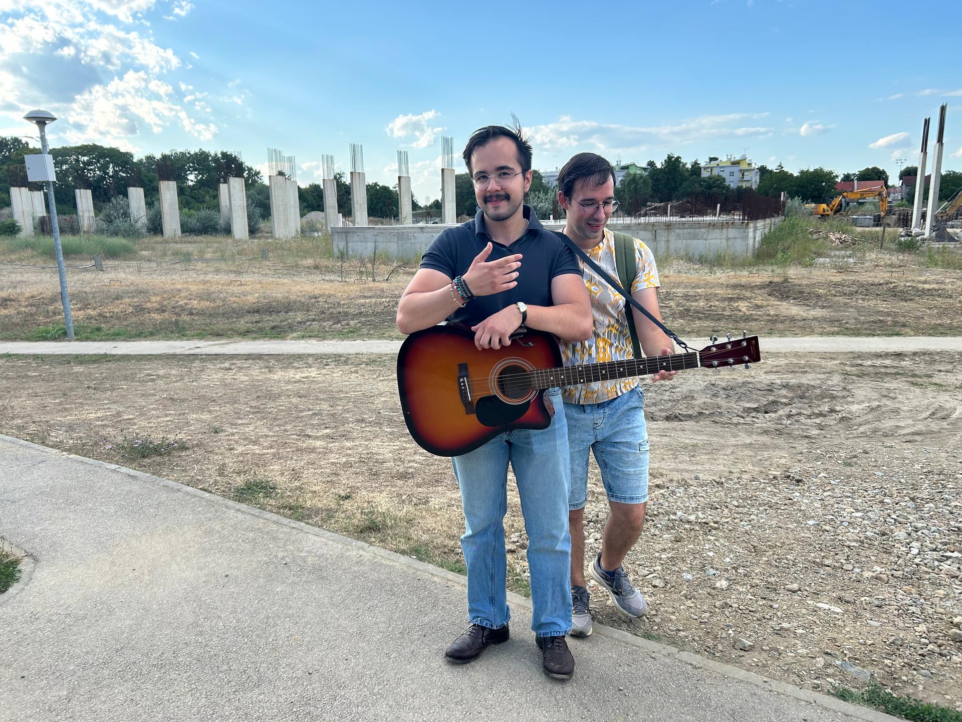 Zwei Männer, einer mit Gitarre, stehen vor einer Bauruine im kroatischen Vukovar Zwei Männer, einer mit Gitarre, stehen vor einer Bauruine im kroatischen Vukovar