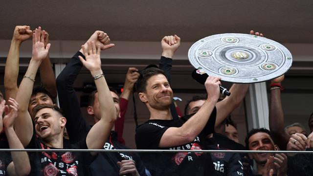 Leverkusen-Trainer Xabi Alonso hält eine Meister-Schale aus Pappe in der Hand.