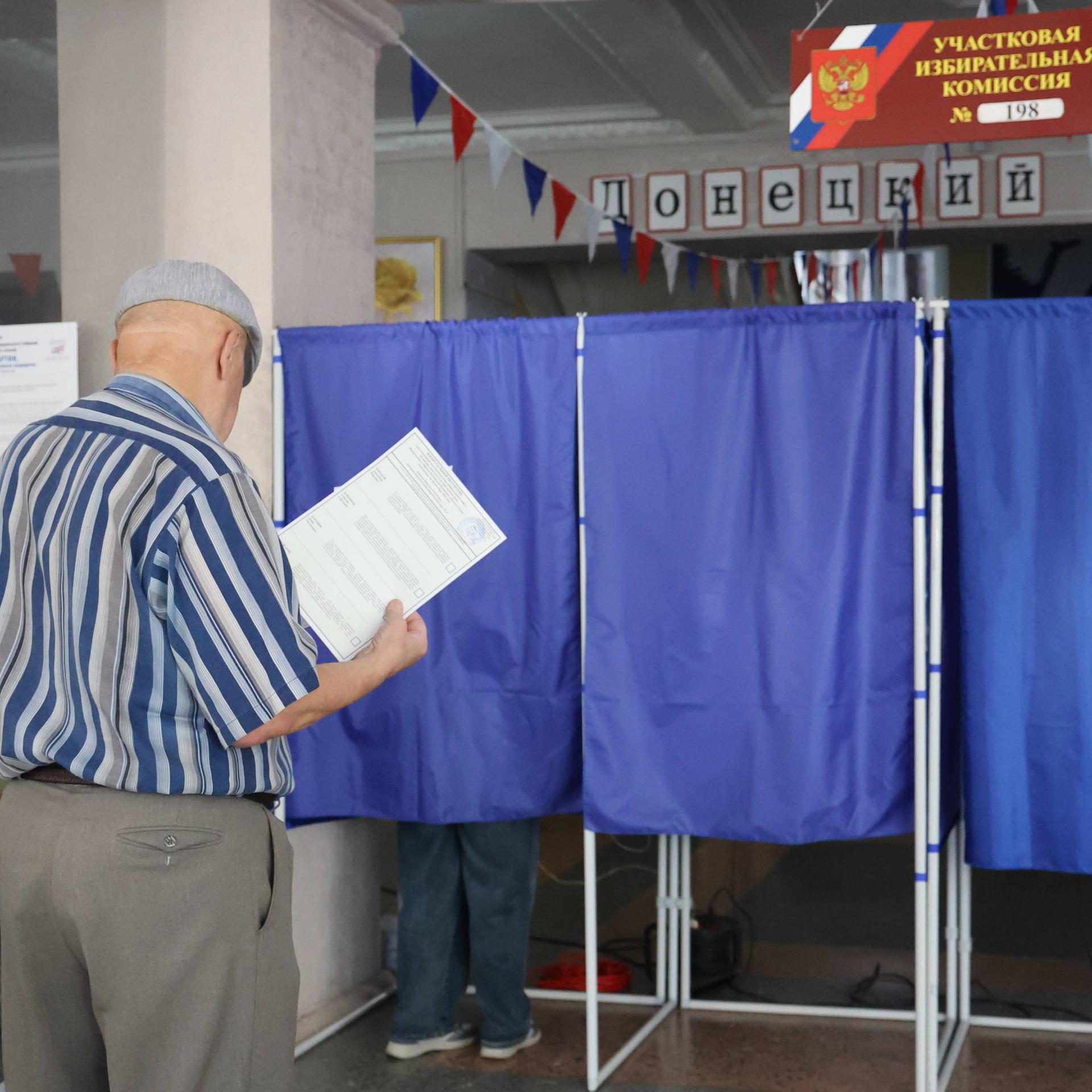 Ein Mann betritt eine Wahlkabine in einem Wahllokal während der Wahlen zur neunten Staatsduma, dem Unterhaus des russischen Parlaments, in Donezk, Russland.