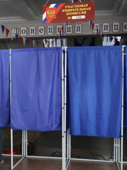 Ein Mann betritt eine Wahlkabine in einem Wahllokal während der Wahlen zur neunten Staatsduma, dem Unterhaus des russischen Parlaments, in Donezk, Russland.