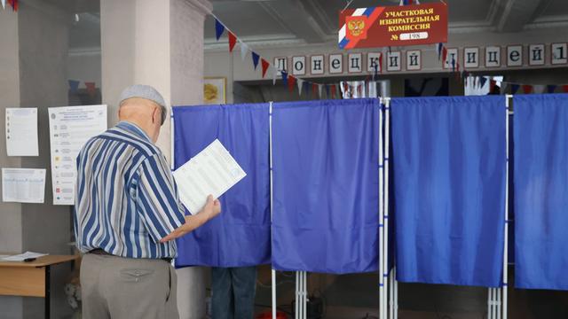 Ein Mann geht in eine Wahl-Kabine.
Er nimmt an einer Wahl in Russland teil.