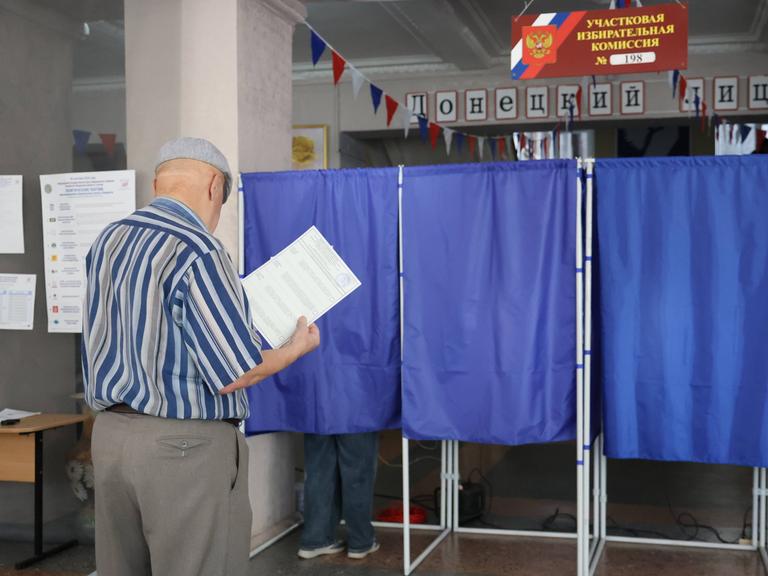 Ein Mann betritt eine Wahlkabine in einem Wahllokal während der Wahlen zur neunten Staatsduma, dem Unterhaus des russischen Parlaments, in Donezk, Russland.