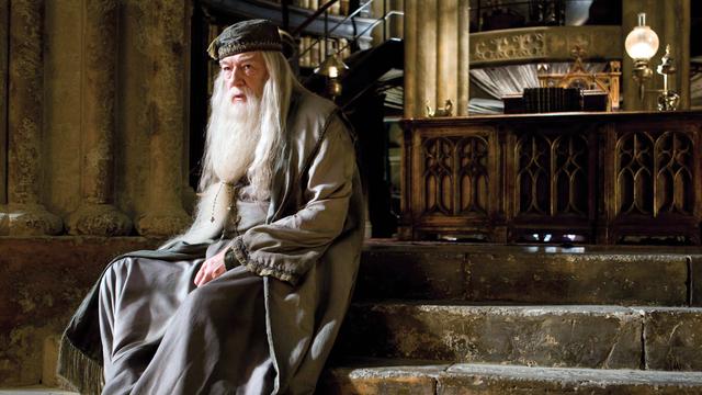 Michael Gambon sitzt als Dumbledore auf einer Treppe in seinem Büro.