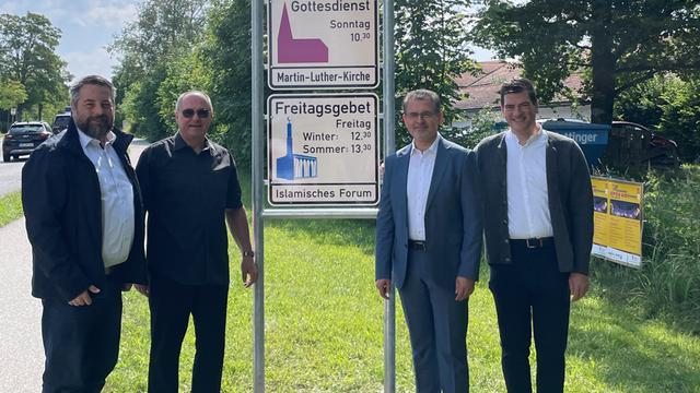Das Foto zeigt vier Männer vor einem Schild mit Infos zum Freitags-Gebet in Penzberg.