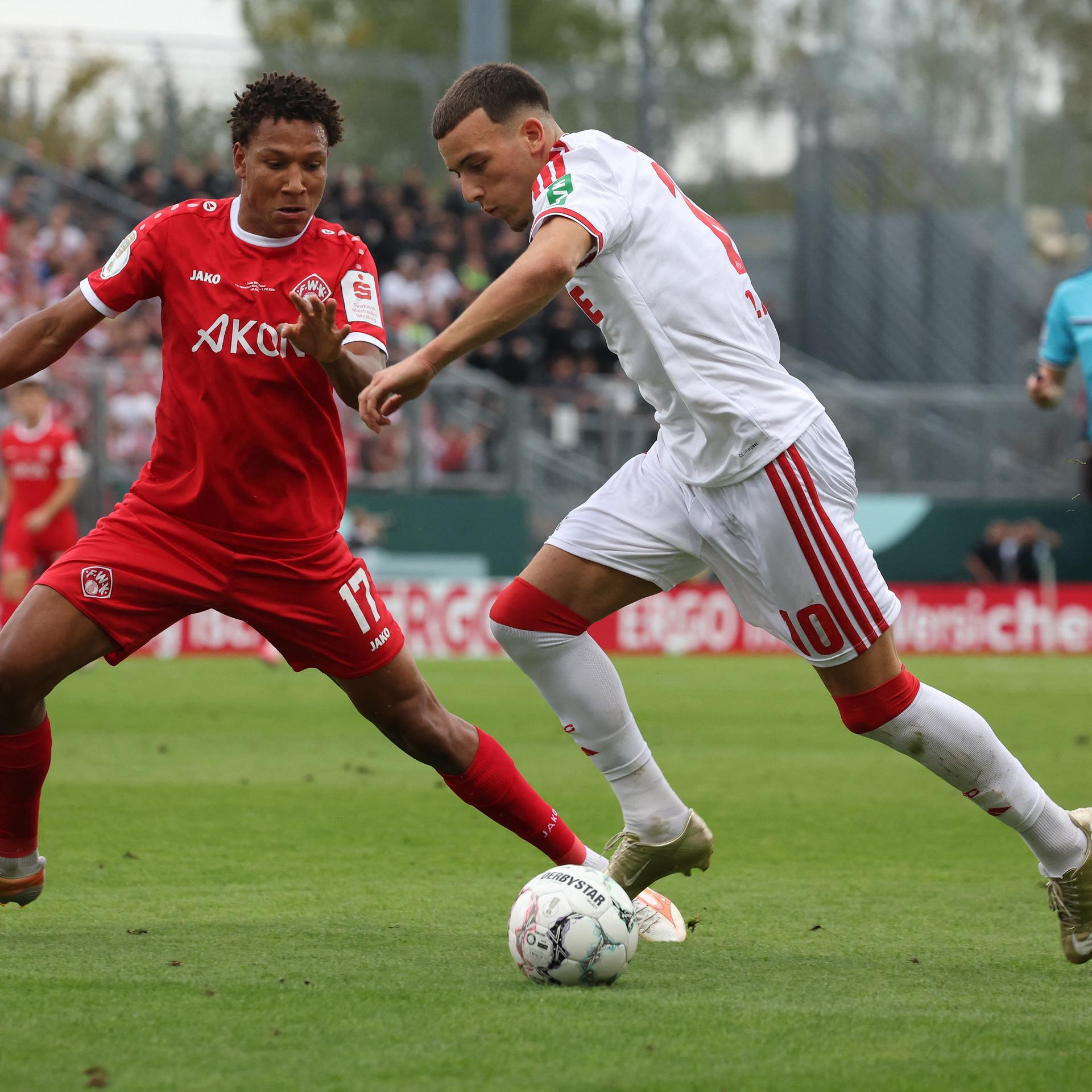 24.08.2026, Bayern, Würzburg: Fußball, Männer: DFB-Pokal, Würzburger Kickers - 1. FC Köln, 1. Runde, AKON Arena, Said El Mala (r) von Köln und Liam Omore von Würzburg, kämpfen um den Ball. Foto: Karl-Josef Hildenbrand/dpa 