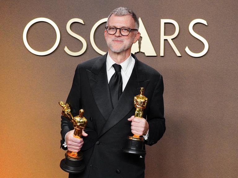 Regisseur Paul Thomas Anderson steht bei der Oscarverleihung mit zwei goldenen Trophäen in den Händen auf der Bühne. 