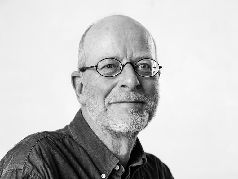 Ein Mann mit Brille und Dreitagebart schaut erfreut in die Kamera