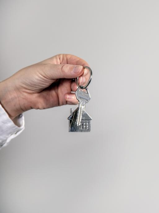Eine Hand hält einen Schlüssel mit einem Hausanhänger.