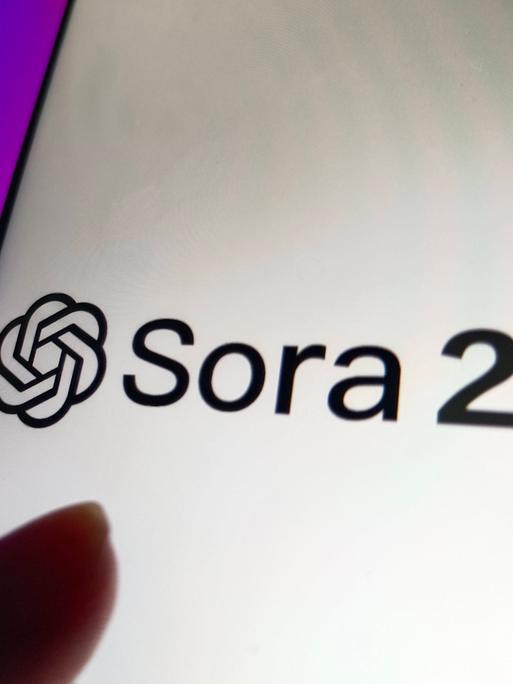 Auf einem Smartphone-Bildschirm leuchtet das Logo der App Sora2 der Firma Open AI. Auf einem Smartphone-Bildschirm leuchtet das Logo der App Sora2 der Firma Open AI.