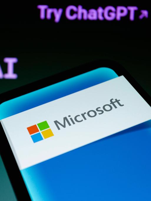Ein Smartphone mit Microsoft-Logo vor einen ChatGPT-Hintergrund.