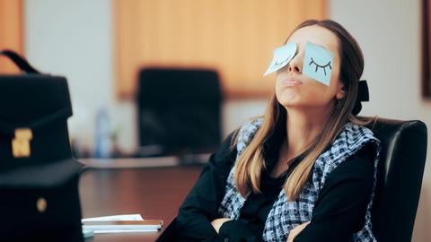 Eine Frau im Büro hat über ihre Augen Post-its geklebt.