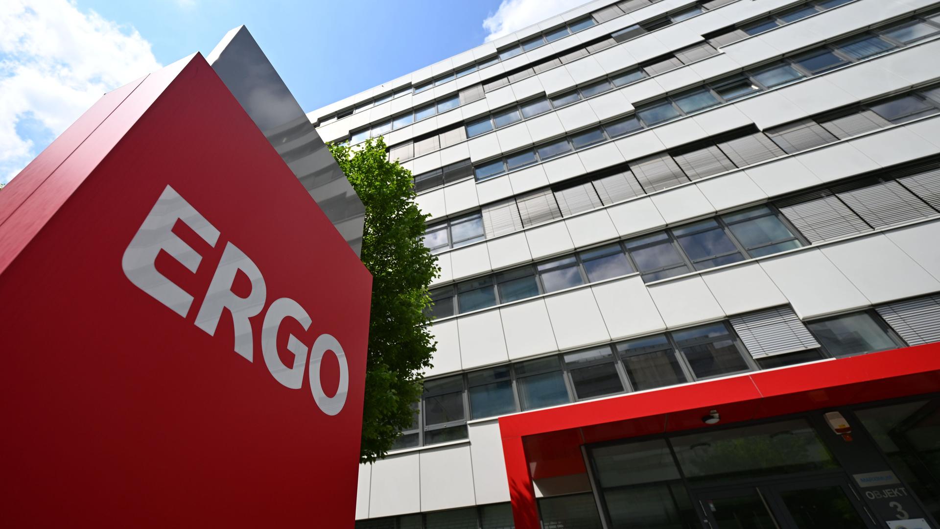 Vor einem hohen Gebäude steht ein rotes Schild mit der Aufschrift "Ergo".