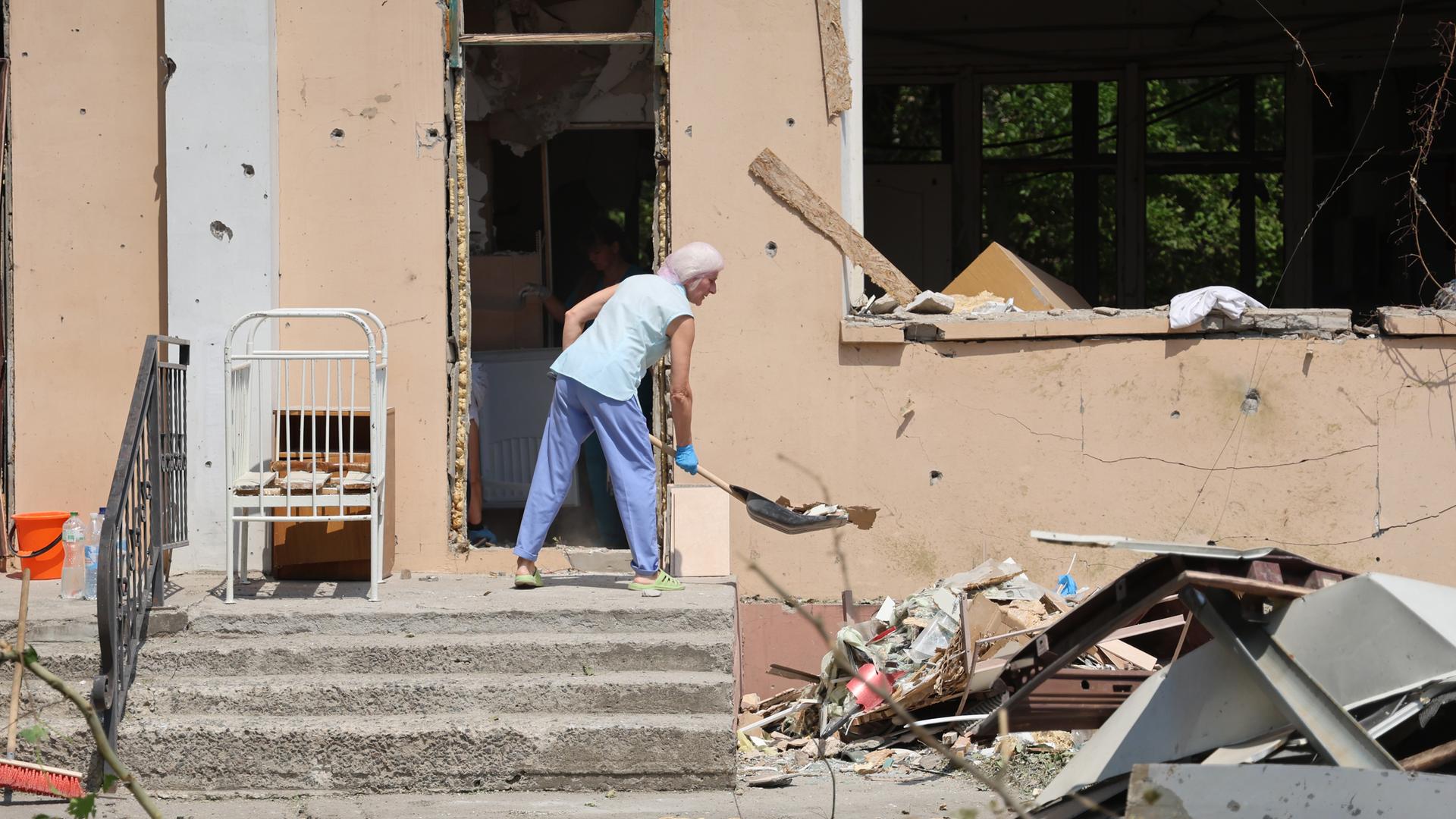 Eine Person räumt in einem durch russischen Beschuss beschädigten Krankenhaus in Cherson Trümmer weg. Eine Person räumt in einem durch russischen Beschuss beschädigten Krankenhaus in Cherson Trümmer weg.