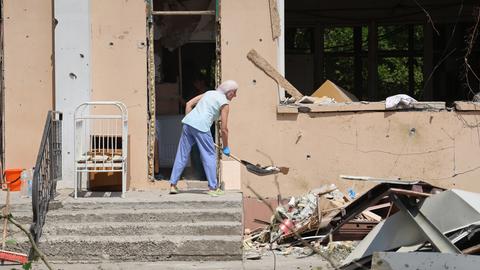 Eine Person räumt in einem durch russischen Beschuss beschädigten Krankenhaus in Cherson Trümmer weg.
