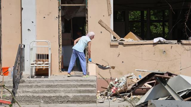 Eine Person räumt in einem durch russischen Beschuss beschädigten Krankenhaus in Cherson Trümmer weg.
