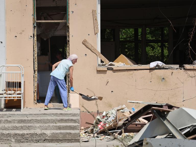 Eine Person räumt in einem durch russischen Beschuss beschädigten Krankenhaus in Cherson Trümmer weg.