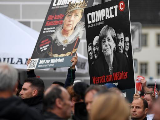 Bei Protesten 2017 halten Demonstranten Plakate in die Höhe, die Titelbilder des Magazins "Compact" mit Kritik an Angela Merkel zeigen.