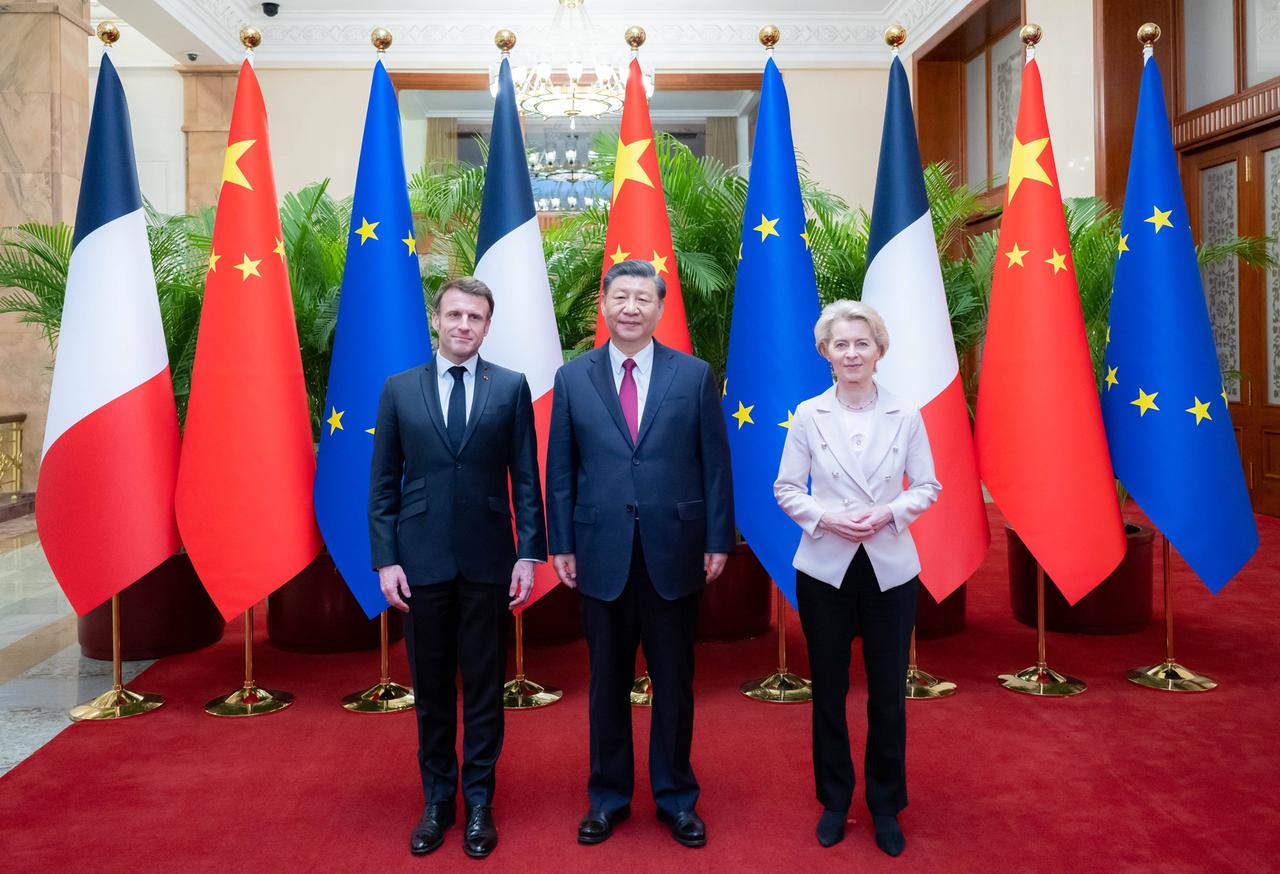 Drei Personen stehen vor der französischen, der chinesischen und der europäischen Flaggen. 