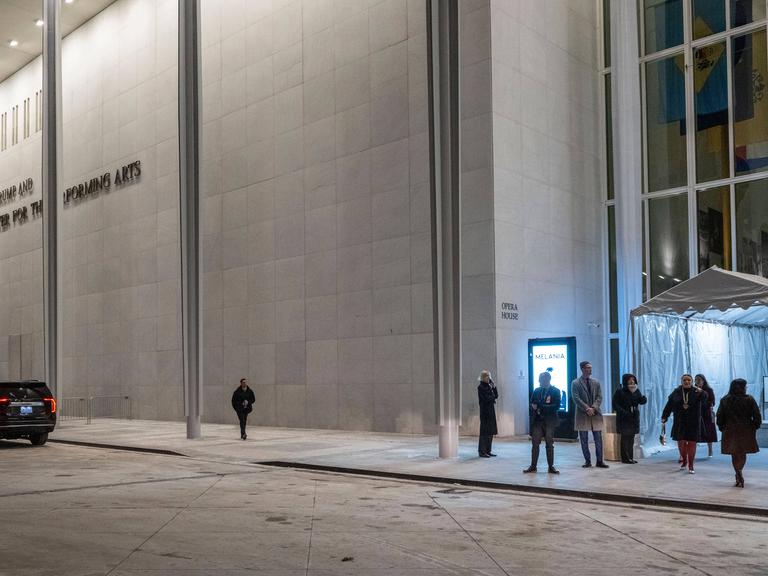 Das Foto zeigt das Eingangsportal des Kennedy-Centers in Washington. Menschen betreten es durch eine Eingangsschleuse.