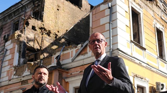 Der deutsche Bundes-Kanzler Friedrich Merz und Wolodymyr Selenskyj, der Präsident der Ukraine, stehen vor einem zerstörten Gebäude in Kiew.