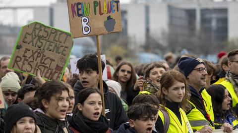 Streikende Jugendliche halten ein Plakat mit der Aufschrift "Es gibt kein Planet B" in die Höhe.