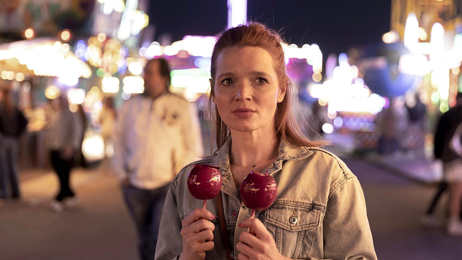 Filmszene aus "Wunderschöner", die Schauspielerin Karoline Herfurth hat rechts und links zwei rote Liebesäpfel in der Hand.