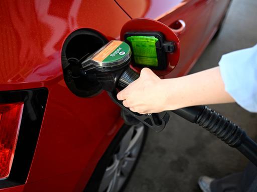 Das Bild zeigt eine Person. Sie betankt ein Auto mit Benzin.