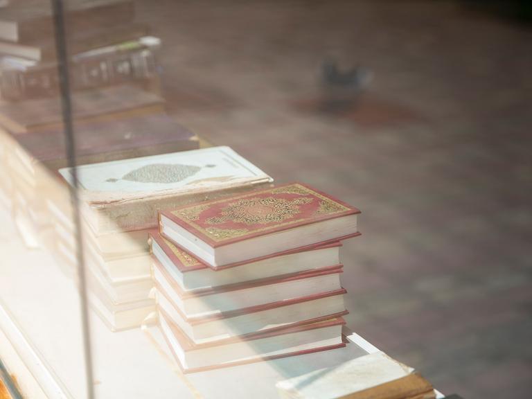 Durch ein Fenster kann man verschiedene Bücherstapelt sehen.