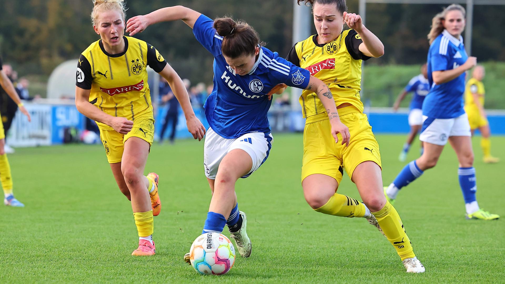 Die Schalker Spielerin legt den Ball an den Dortmunder Spielerinnen vorbei.