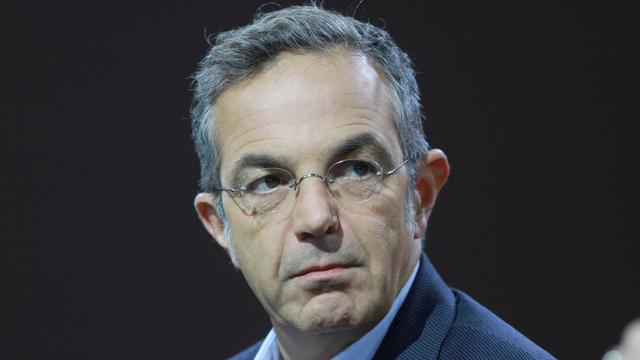 Navid Kermani, mit Brille, in einem blauen Sakko, sitzt auf einem Podium. 