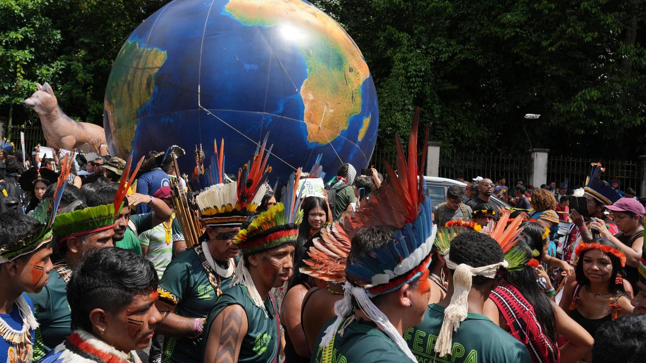 Indigene Aktivisten protestieren am Rande der UN-Klimakonferenz und tragen eine Erdkugel in der Menge 