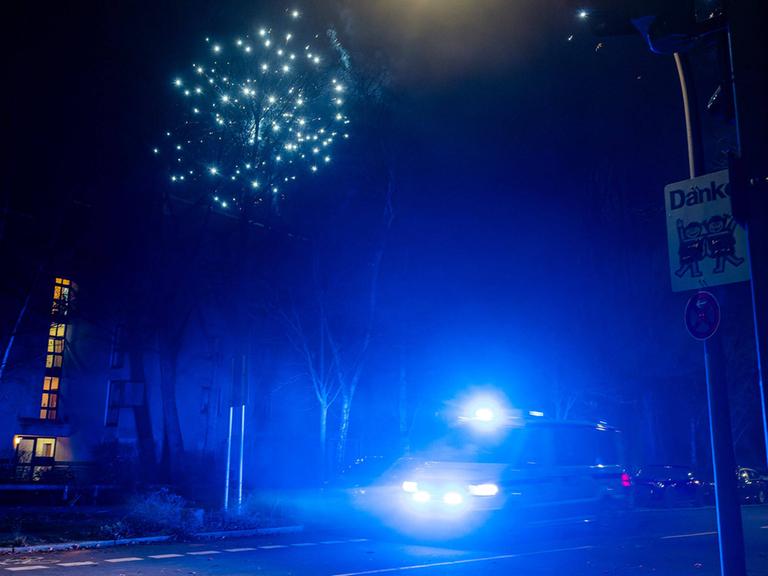 In der Silvesternacht 2022/23 fährt ein Einsatzfahrzeug mit Blaulicht durch eine Straße in Berlin.