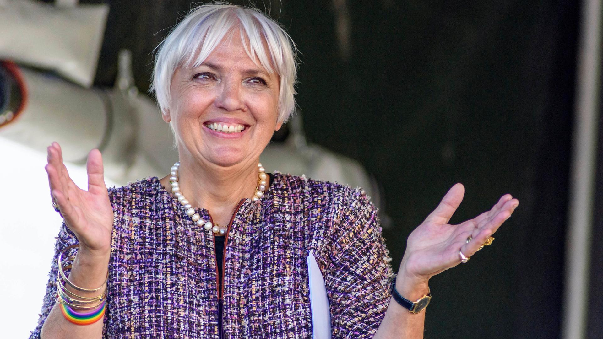 Claudia Roth lächelnd mit ausgebreiteten Armen.