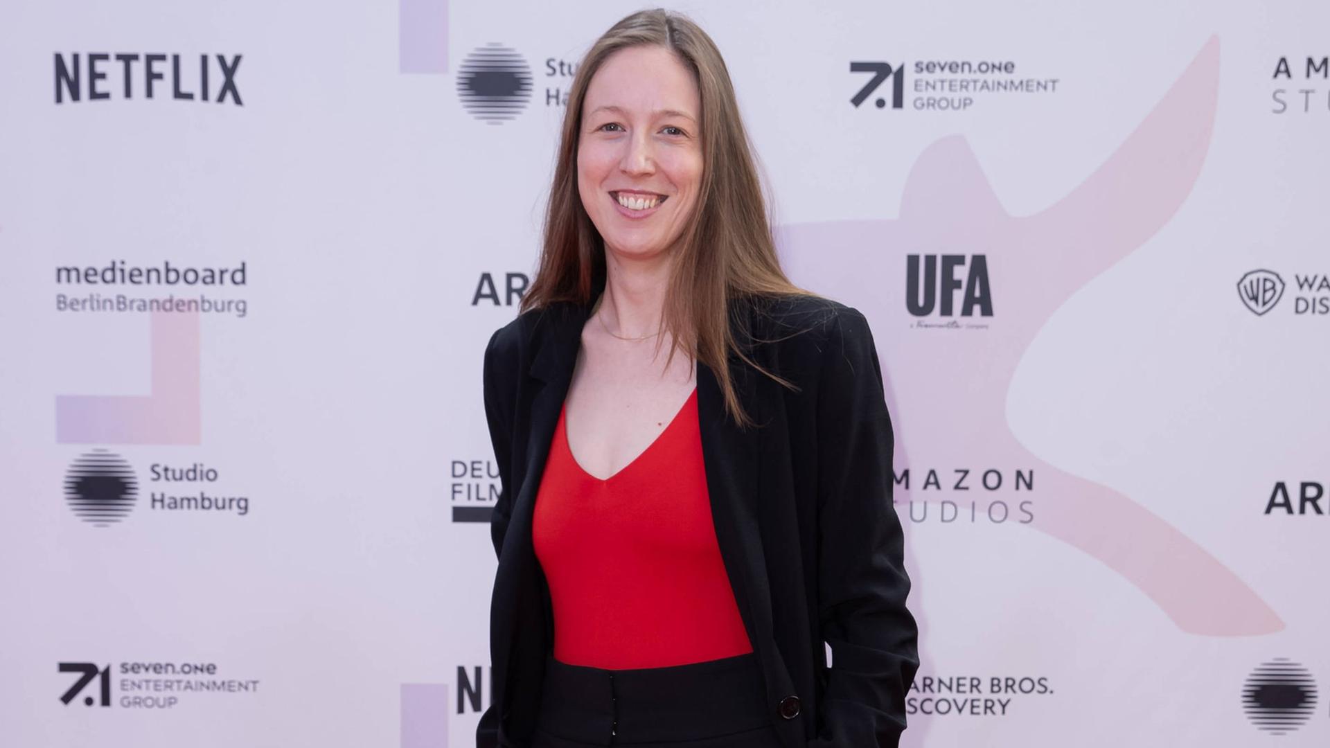 Kamerafrau Caroline Spreitzenbart steht vor einer Sponsorenwand, wie sie bei Filmfestivals üblich ist. Kamerafrau Caroline Spreitzenbart steht vor einer Sponsorenwand, wie sie bei Filmfestivals üblich ist.