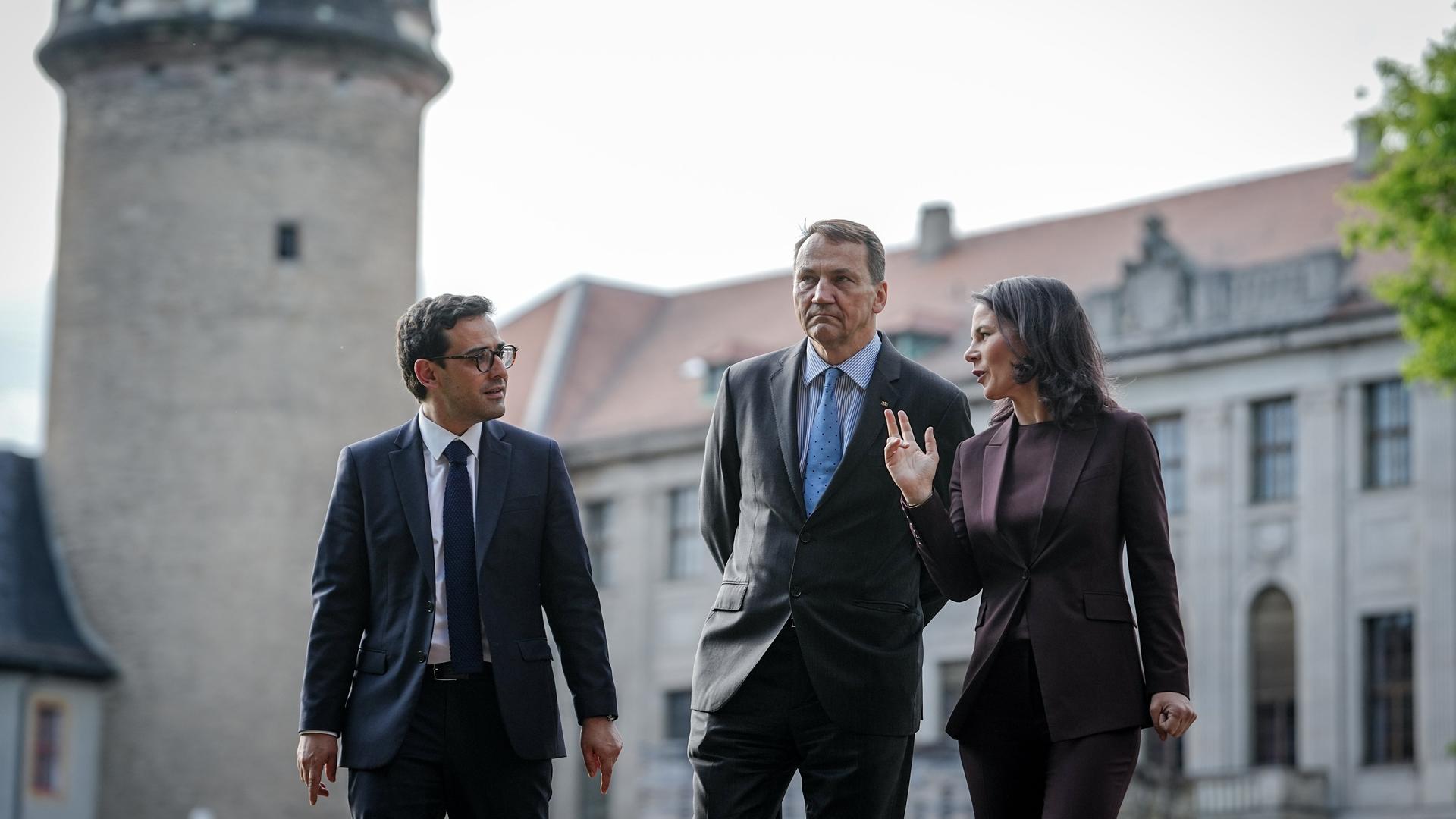 Bundesaußenministerin Annalena Baerbock geht im Rahmen des Weimarer Dreiecks mit ihren Amtskollegen Stéphane Séjourné (l) aus Frankreich und Radoslaw Sikorski aus Polen durch einen Park.