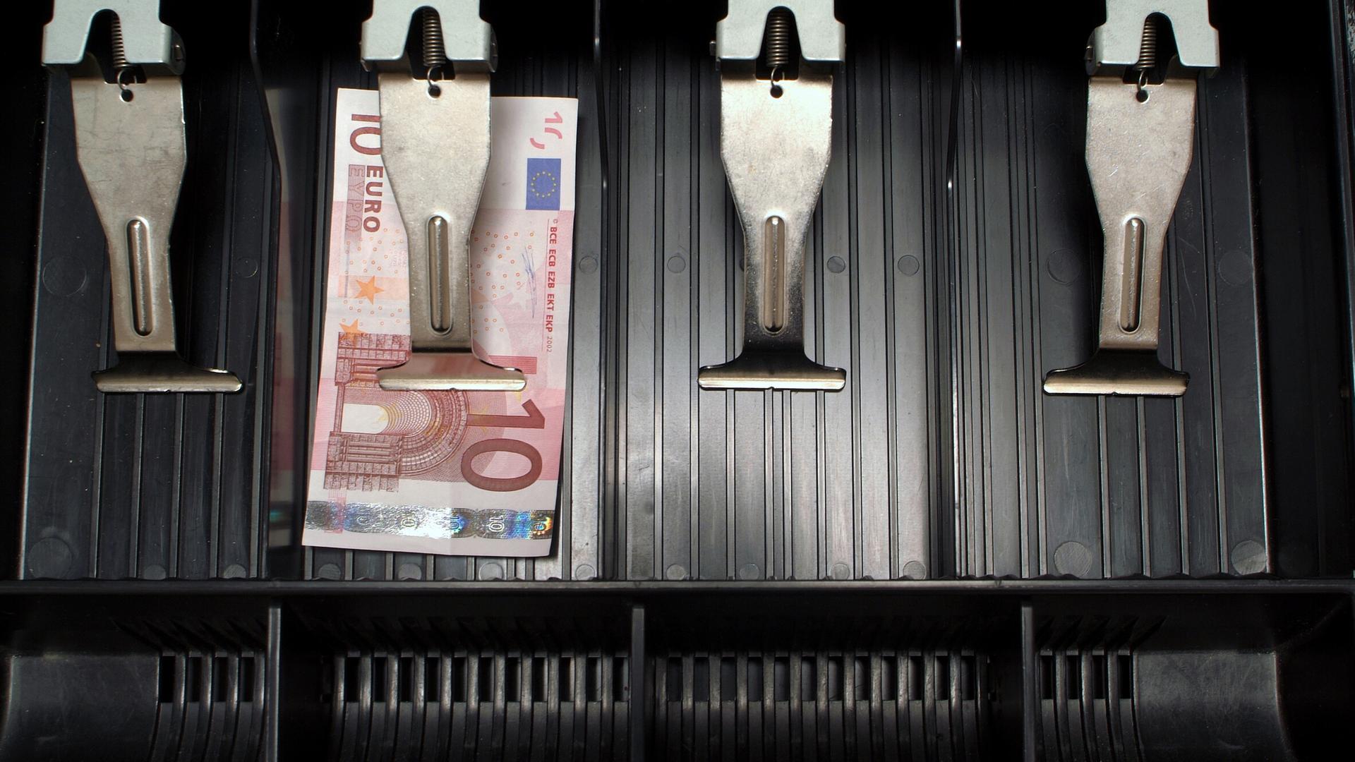 In einer ansonsten leere Kasse liegt ein einzelner Zehn-Euro-Schein.