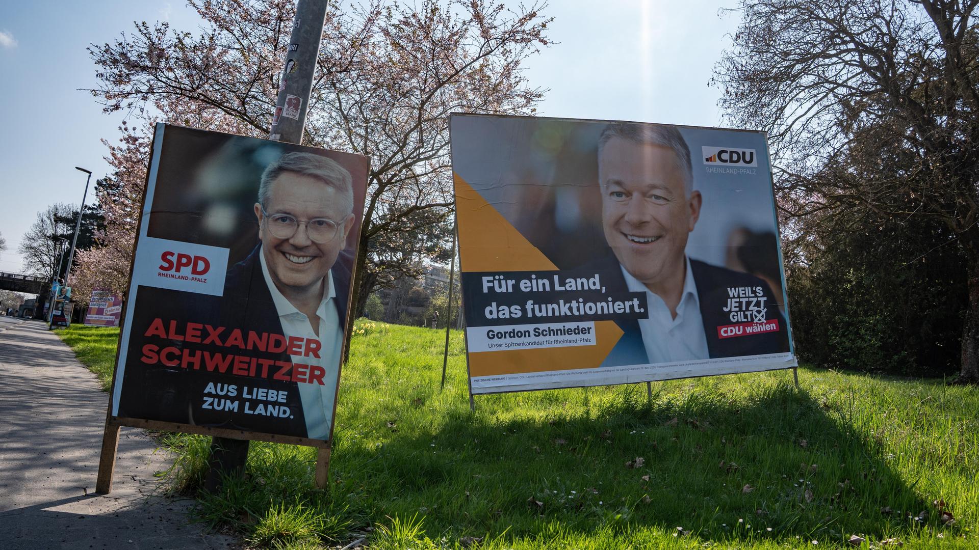 In der rheinland-pfälzischen Landeshauptstadt Mainz stehen auf einer Wiese am Straßenrand Wahlplakate der SPD mit Alexander Schweitzer (l.) und der CDU mit Gordon Schnieder (r.). Sie treten bei der Landtagsahl als Spitzenkandidaten an.