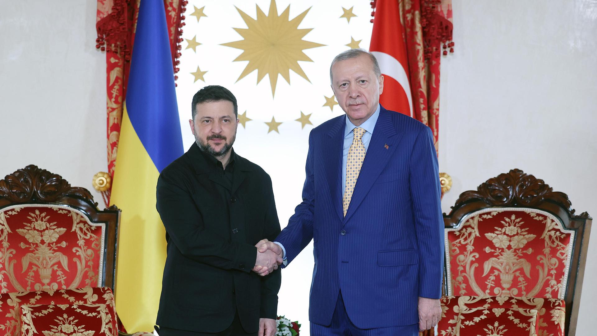 Der ukrainische Präsident Selenskyj (l.) bei seinem Treffen mit dem türkischen Staatschef Erdogan in Istanbul. Beide stehen nebeneinander und schütteln sich die Hand. Im Hintergrund sind die Flaggen beider Länder zu sehen sowie zwei große Sessel.
      